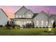 Two-story white farmhouse exterior with landscaping at dusk at 13109 Brooklyn Skylar Way, Huntersville, NC 28078