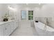 Modern bathroom with a soaking tub, marble floors, double vanity, and shuttered windows for natural light at 2809 Glendale Rd, Charlotte, NC 28209