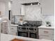 Close up shot of a spacious kitchen featuring stainless steel appliances, stone countertops, custom backsplash, and white cabinetry at 2809 Glendale Rd, Charlotte, NC 28209