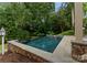Backyard pool features stone coping and walls with mature trees at 2809 Glendale Rd, Charlotte, NC 28209