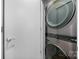 A space saving, stainless steel, stacked washer and dryer next to a grey door at 287 Mcdonald Ave, Charlotte, NC 28203