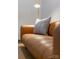 A tan leather couch is accented with a gray-and-white pillow in a simply styled living space at 287 Mcdonald Ave, Charlotte, NC 28203