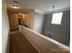 Upstairs hallway featuring neutral carpeting, fresh paint, and a stylish pendant light near the stairwell at 5934 Hickory Hollow Ct, Harrisburg, NC 28075