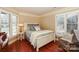 A bright bedroom features a white framed bed, windows with shutters, and wood floors at 615 Portside Dr, Davidson, NC 28036