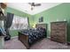 Vibrant bedroom with green walls, a ceiling fan, and a cozy bed with space-themed bedding at 7602 Rolling Meadows Ln, Huntersville, NC 28078