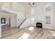 Light-filled living room with a cozy fireplace, staircase, and neutral hardwood floors at 132 Elizabeth Hearth Rd, Mooresville, NC 28115