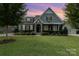 Gray two-story house with stone accents, landscaping, and a three-car garage at dusk at 1320 Torrens Dr, Wesley Chapel, NC 28110