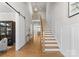 Spacious foyer with hardwood floors, white wainscoting, staircase and modern chandelier at 831 Naples Dr, Davidson, NC 28036