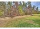 Well-maintained backyard with retaining wall, grass and woods at 11419 Rising Star Ct, Charlotte, NC 28215