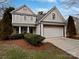 Two-story house with beige siding, stone accents, and a two-car garage at 2507 Oakdale Creek Ln, Charlotte, NC 28216