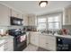 Bright kitchen with white cabinetry, a double sink, and black appliances including a range and microwave at 30 Hunter St, York, SC 29745