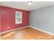Bedroom with a dark red accent wall and hard wood floors at 310 Black Rock School Rd, Cherryville, NC 28021