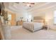 Bright bedroom with neutral tones, tray ceiling, carpet flooring, and a dresser with decorative plants at 712 Kenway Loop, Mooresville, NC 28117