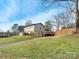 Exterior view of a multi-level home showcasing its spacious yard, wooden deck, and paved driveway at 7131 Thorncliff Dr, Charlotte, NC 28210