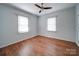 A bright bedroom with two windows, blinds, hardwood floors, and a ceiling fan for comfortable living at 1213 Cloninger Ave, Gastonia, NC 28052