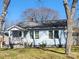 Charming light blue home featuring a welcoming front porch, well-maintained lawn and a beautiful treed front yard at 128 N Oak St, Salisbury, NC 28146