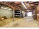 Wide horse stall with shelving, concrete walls, open ceiling with exposed rafters and ample open space at 1354 Mirror Lake Rd, Lincolnton, NC 28092