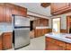 Cozy kitchen featuring wood cabinetry, stainless steel refrigerator and view to brick fireplace at 1354 Mirror Lake Rd, Lincolnton, NC 28092