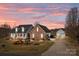Beautiful brick home with manicured landscaping, long driveway, and detached garage under a gorgeous sunset sky at 144 Cameron Dr, Salisbury, NC 28147