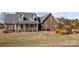 View of the charming front yard, red brick facade, and welcoming front porch at 144 Cameron Dr, Salisbury, NC 28147