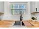 Close-up of kitchen sink, faucet, wooden countertops, and view to the backyard at 4125 Rivendell Ln, Mint Hill, NC 28227