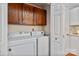 Convenient laundry area featuring a white washer and dryer, with wood cabinets and a door for added privacy at 6717 Paces Ferry Ln, Charlotte, NC 28226