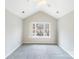 Inviting bedroom with a vaulted ceiling, large window, and plush gray carpet at 7719 Abigail Glen Dr, Charlotte, NC 28212