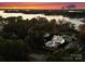 The twilight aerial view showcases the home's pool and patio, nestled among mature trees near a tranquil lake at 117 Yellow Jacket Cir, Mooresville, NC 28117