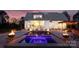 The backyard at dusk features a luxury pool, spa, and outdoor lighting, ideal for evening relaxation and entertainment at 117 Yellow Jacket Cir, Mooresville, NC 28117