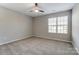 This bedroom has a ceiling fan, a large window, and neutral walls and carpet for comfort at 129 Woodbridge Cir, Mount Holly, NC 28120