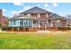 A backyard view showcasing the home's brick facade, sunroom, white railing deck, and manicured landscaping at 201 Limerick Dr, Matthews, NC 28104