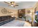 Cozy living room featuring a brick fireplace, hardwood floors, ceiling fan, and comfortable leather sofa at 2370 Old Mountain Rd, Statesville, NC 28625