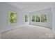 Bright bedroom features neutral carpet, light gray walls and abundant natural light from large windows overlooking lush greenery at 2418 Lexington Approach Dr, Charlotte, NC 28262