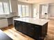 Large kitchen island with seating, white countertop, black cabinetry, and lots of natural light at 2418 Lexington Approach Dr, Charlotte, NC 28262
