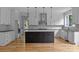 Modern kitchen with white cabinets, black island, stainless steel appliances, and herringbone backsplash at 2418 Lexington Approach Dr, Charlotte, NC 28262