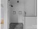 Luxurious shower with marble-look tile, a black rainfall showerhead, and stylish hexagon tile flooring at 2418 Lexington Approach Dr, Charlotte, NC 28262