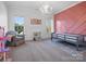 Bright bedroom with a playful pink accent wall, large windows, cozy chair and modern chandelier at 2553 Cozy Cove Dr, York, SC 29745