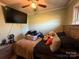 Comfortable bedroom features a ceiling fan, a window, and a bed with plush bedding and a side table at 32269 Pennington Rd, Albemarle, NC 28001