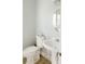 Charming bathroom with white fixtures, pedestal sink, and a round mirror at 55 Academy Nw Ave, Concord, NC 28025