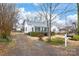 Home exterior with siding, trimmed hedges, small staircase, large windows, and gravel driveway at 63 3Rd Nw St, Concord, NC 28027