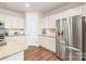 Well-appointed kitchen featuring stainless steel refrigerator, white cabinets, granite counters and hardwood floors at 8500 Union Central Ct, Waxhaw, NC 28173