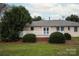 Backyard with a deck, manicured bushes, trees, and a well-maintained lawn at 1101 S Wendover Rd, Charlotte, NC 28211