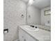 Small bathroom with floral wallpaper, white vanity, and mirror for a simple and elegant space at 6815 Cabot Cir, Charlotte, NC 28226