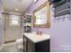 Well-lit bathroom featuring a decorative mirror, modern vanity, and a tiled shower with natural light at 1148 Rita Ave, Statesville, NC 28677