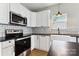 Kitchen with black countertops and appliances, white cabinets, tile backsplash, and hardwood floors at 1836 Danny Ct, Matthews, NC 28105