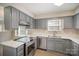 Well-lit kitchen featuring gray cabinets, stainless steel appliances, and a dual basin sink below a window at 8137 Sheringham Way, Charlotte, NC 28227