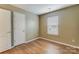 This neutral bedroom features wood-look floors, a large window, and a door to the hall at 830 Wilcrest Ct, York, SC 29745