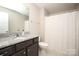 Well-lit bathroom featuring a granite countertop, dark wood cabinetry, and a shower with a white curtain at 108 Hillston Ln, Mooresville, NC 28115