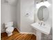 Powder room featuring a pedestal sink, oval mirror, and hardwood floors at 12025 Willingdon Rd, Huntersville, NC 28078