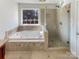 Luxurious bathroom featuring a jetted tub, glass enclosed shower and tile surround at 12025 Willingdon Rd, Huntersville, NC 28078